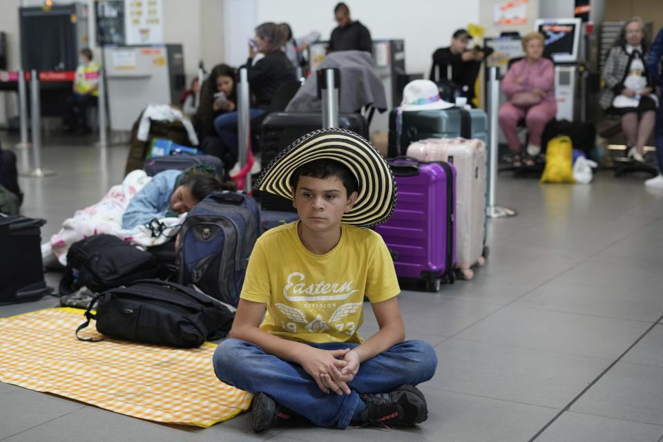 Viva Air passengers sit at the check-in area after the low-cost airline suspended its operations at the El Dorado International Airport in Bogota, Colombia, Tuesday, Feb. 28, 2023. The airline is awaiting the completion of an integration process with a group of airlines that must be approved by the Colombian authorities. (AP Photo/Fernando Vergara)