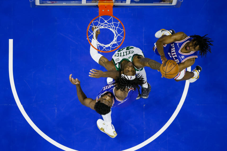 Boston Celtics' Robert Williams III, center, goes up for the rebound against Philadelphia 76ers' Tyrese Maxey, right, and Joel Embiid, left, during the first half of an NBA basketball game, Friday, Jan. 14, 2022, in Philadelphia. (AP Photo/Chris Szagola)