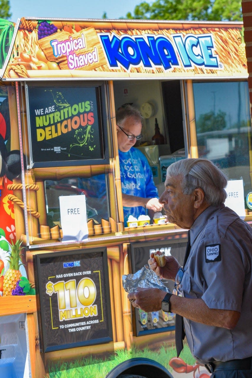 Assistant Service Plaza Manager Daniel Sengstock enjoys a hot dog near the Kona Ice truck, where turnpike visitors received free shaved ice samples.