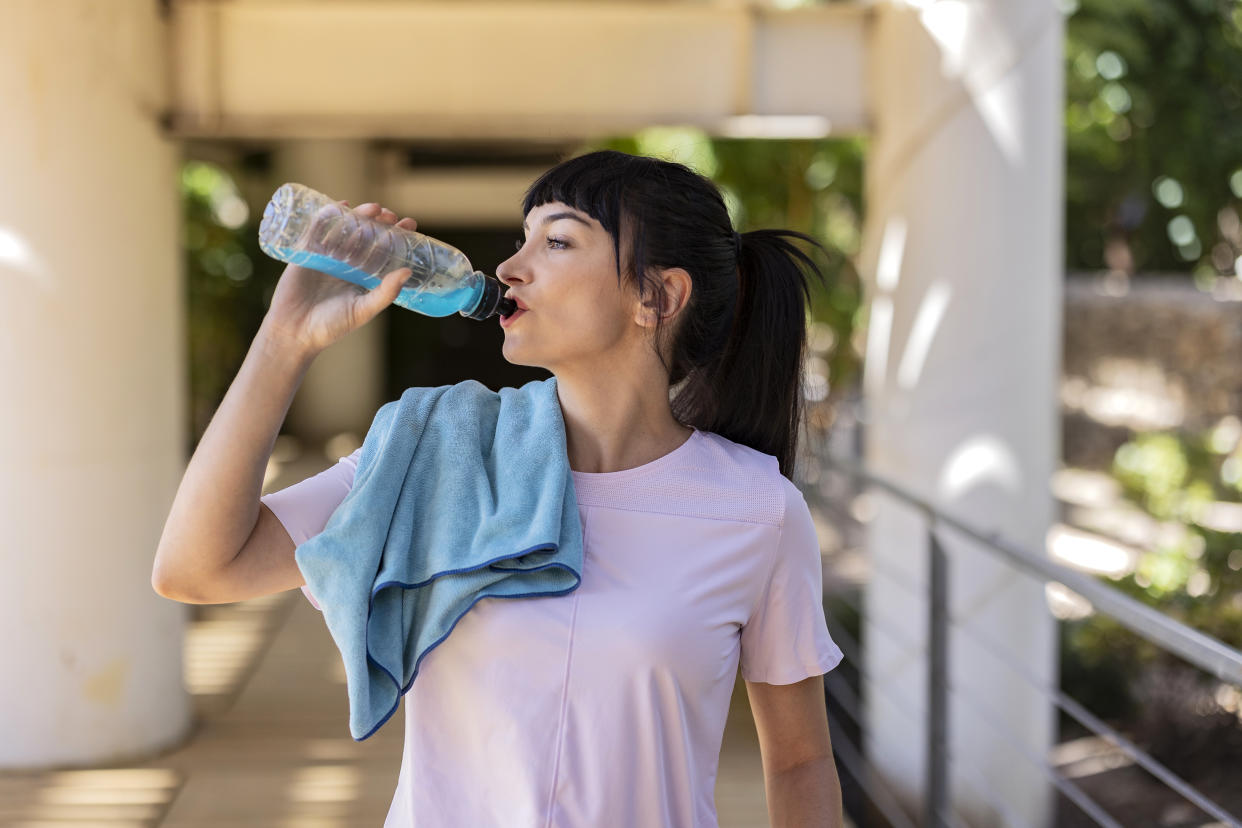 amazon cooling towel, cooling towel, amazon, someone with a towel on their shoulder while drinking out of a bottle outside