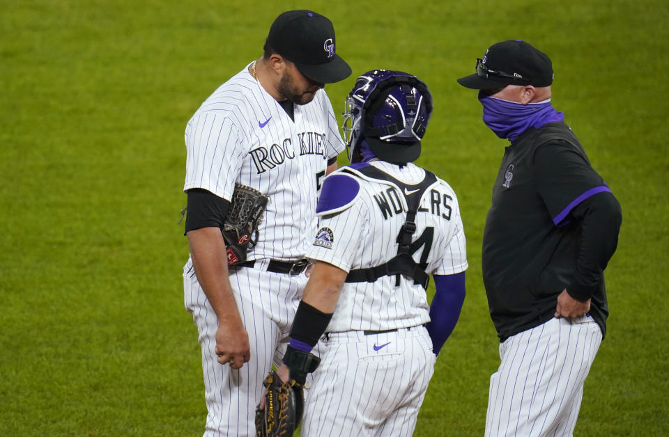 Colorado Rockies relief pitcher Carlos Estevez, left, confers with catcher Tony Wolters and pitching coach Steve Foster after Estevez gave up an RBI double to Los Angeles Dodgers' Corey Seager during the seventh inning of a baseball game Thursday, Sept. 17, 2020, in Denver. (AP Photo/David Zalubowski)