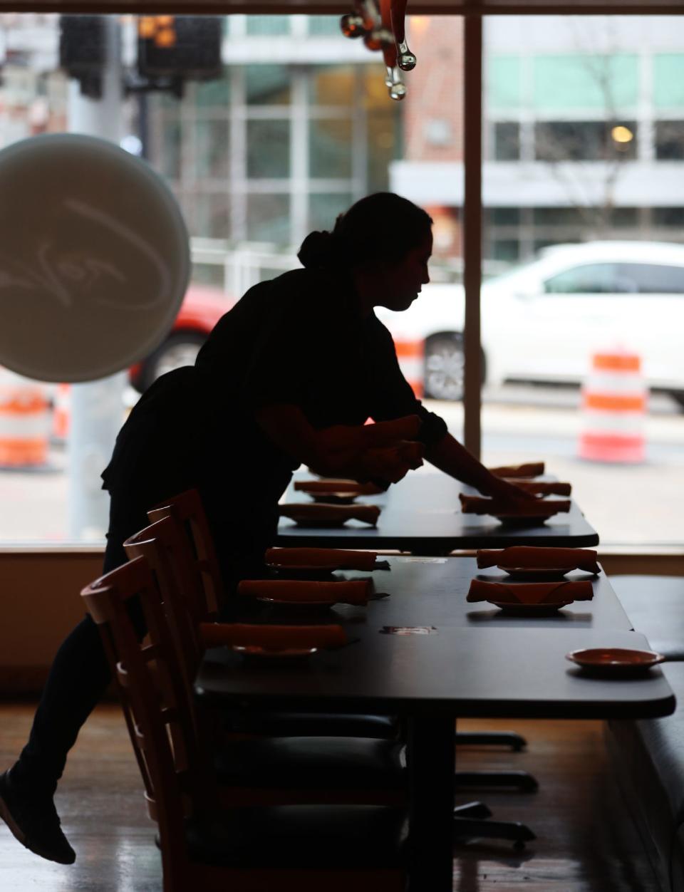 Zahra Yusufi, a server/bartender at Crave, sets tables in the Akron eatery.