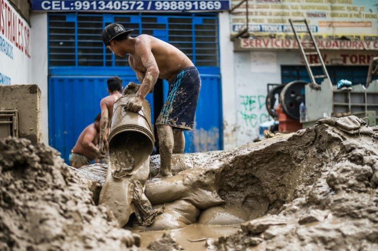 Residents of a populous district of Lima remove from their house mud, debris and water left by a flash flood, on March 19, 2017