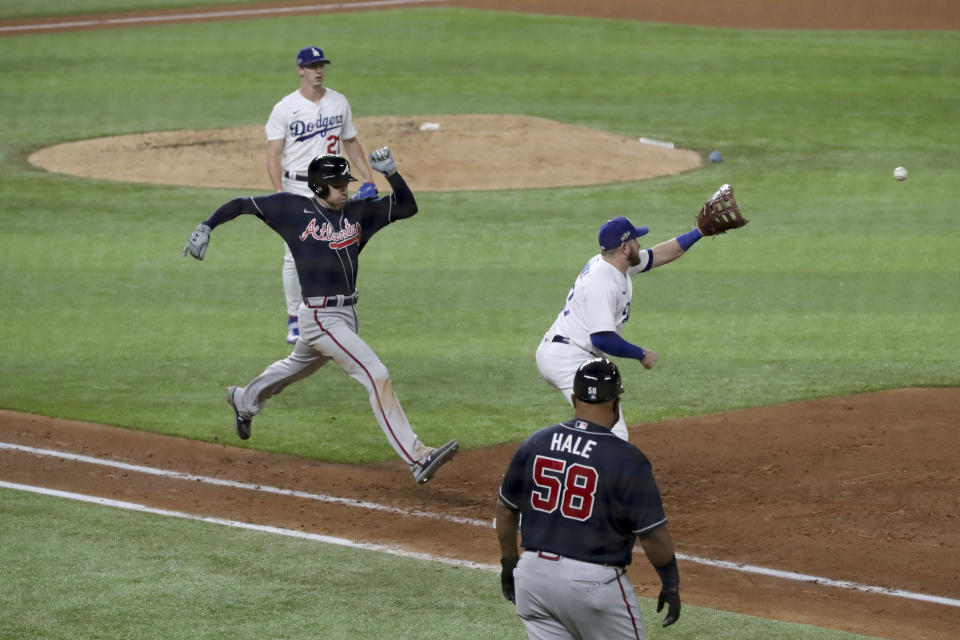 Atlanta Braves first baseman Freddie Freeman, left, is out at first base on a ground ball fielded by Los Angeles Dodgers first baseman Max Muncy during the fifth inning in Game 1 Monday, Oct. 12, 2020, for the best-of-seven National League Championship Series at Globe Life Field in Arlington, Texas. Also shown on the play is Atlanta Braves first base coach DeMarlo Hale (58). (Curtis Compton/Atlanta Journal-Constitution via AP)