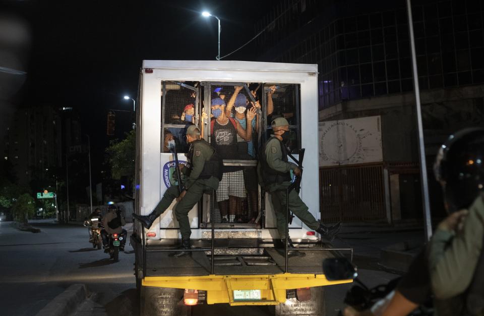 Men who were detained for not complying with COVID-19 regulations by breaking curfew or attending block parties, are transported in a police van, in the Petare neighborhood of Caracas, Venezuela on Aug. 8, 2020. Associated Press photographer Ariana Cubillos says the image “made me realize COVID-19 has caged us and taken away our freedom of movement. It struck me as ironic that the same authorities enforcing the curfew were putting these men at risk of contagion by breaking the very social distancing rules authorities put in place.” (AP Photo/Ariana Cubillos)