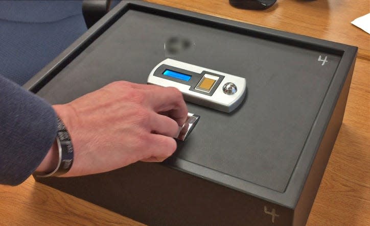 A Jay County school official demonstrates how their biometric gun safes open after scanning an approved staff member's fingertip.