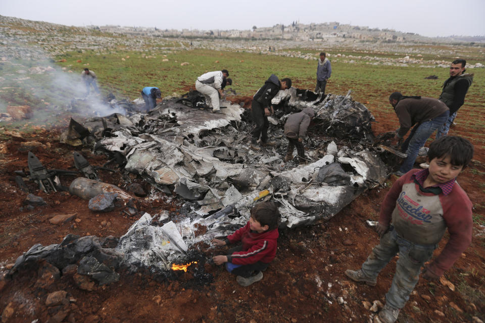 Syrians gather around a wreckage of a government military helicopter that was shot down in the countryside west of the city of Aleppo, Friday, Feb. 14, 2020. (AP Photo/Ghaith Alsayed)