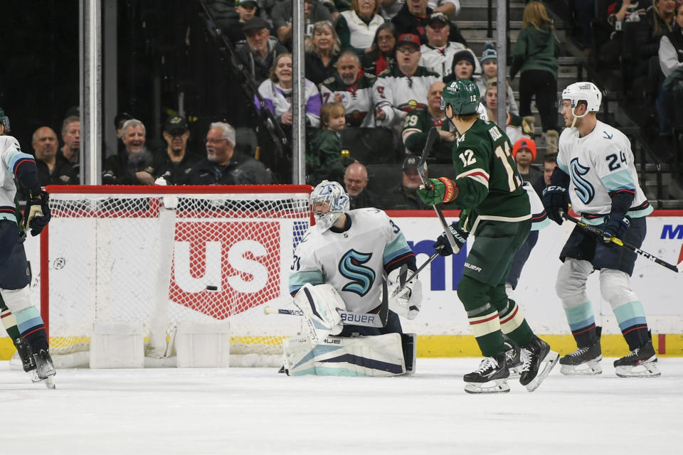 Minnesota Wild left wing Matt Boldy (12) watches his shot hit the back of the net as he scores past Seattle Kraken goalie Philipp Grubauer, left, as Kraken defenseman Jamie Oleksiak (24) looks on during the second period of an NHL hockey game Monday, March 27, 2023, in St. Paul, Minn. (AP Photo/Craig Lassig)