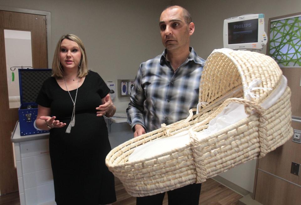 Erin and Tony Maroon of North Canton hold a cooling bassinet that includes a CuddleCot the couple donated to the neonatal intensive care unit at Akron Children's Hospital in 2017.