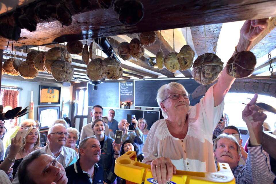 Pub employee Margaret Utteridge, 74, who has worked at The Bell Inn, High Road, Horndon-on-the Hill, Essex since 1984, hangs a hot cross bun from a beam which has been a tradition at the inn since 1906. (Photo by Nick Ansell/PA Images via Getty Images)