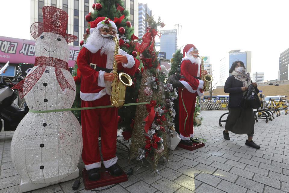 A woman wearing a face mask as a precaution against the coronavirus passes by Christmas decorations outside a shopping mall in Seoul, South Korea, Friday, Nov. 27, 2020. South Korea's daily virus tally hovered above 500 for the second straight day, as the country's prime minister urged the public to stay home this weekend to contain a viral resurgence. (AP Photo/Ahn Young-joon)