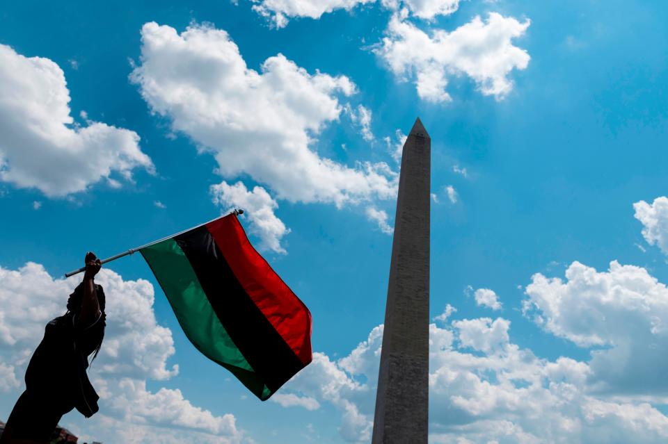 Marah O'Neal, waves a Pan-African flag as she attends a small rally against racism in the U.S. next to the Washington Memorial in Washington, DC, on July 4, 2020.