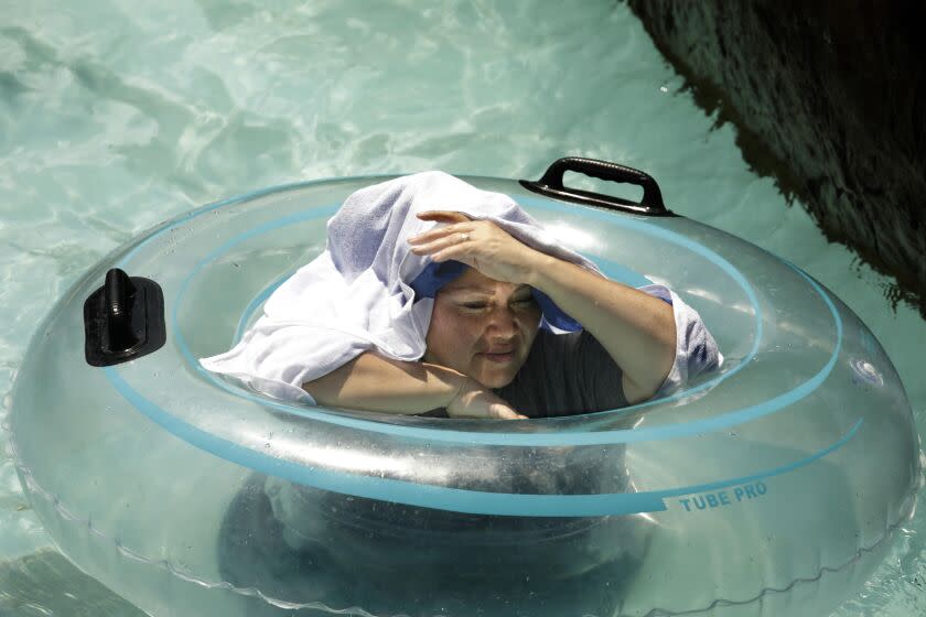 PALMDALE, CA - JULY 11, 2021 - - A woman tries to create her own shade under a towel while cooling off at Dry Town Water Park in Palmdale where temperatures reached 108 degrees by 3 p.m. Sunday on July 11, 2021. (Genaro Molina / Los Angeles Times)