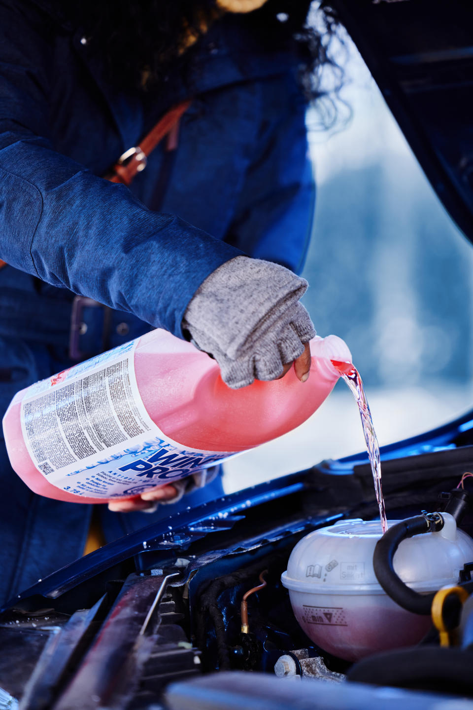 Woman topping up car using winter washer fluid from Canadian Tire