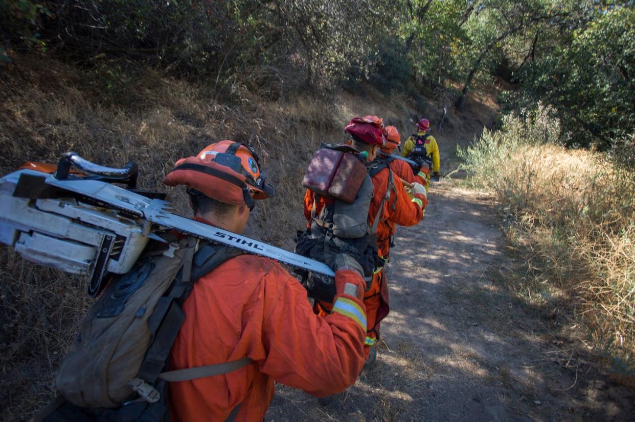 Inmate fire crews work alongside professional fire crews and do the same work. But they receive little, if any, pay. <a href="https://www.gettyimages.com/detail/news-photo/inmate-firefighters-from-oak-glen-conservation-camp-march-news-photo/860662918" rel="nofollow noopener" target="_blank" data-ylk="slk:David McNew/AFP via Getty Images;elm:context_link;itc:0;sec:content-canvas" class="link ">David McNew/AFP via Getty Images</a>