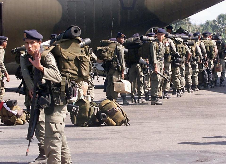 A member of the Indonesian Mobile Police Brigade tries to stop a photographer from taking pictures of his troops boarding an Indonesian Air Force transport plane at Dili Airport in October 1999. At the time, around 100 Indonesian troops were departing for Jakarta, as part of troop withdrawal after East Timor voted for independence from Indonesia. <em>Photo by ROMEO GACAD/AFP via Getty Images</em>