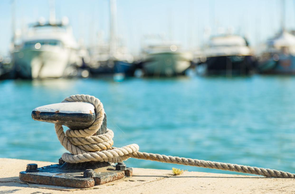 Mooring rope and bollard on sea water and yachts background