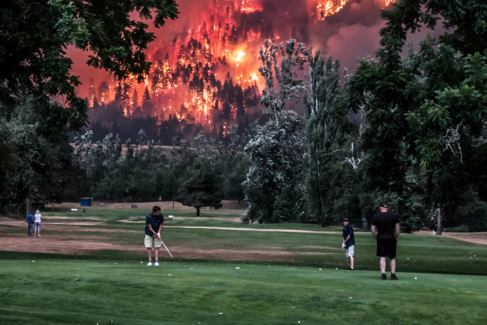 The Eagle Creek wildfire burns as golfers play at the Beacon Rock Golf Course in North Bonneville, Washington, on September 4, 2017. (Photo: REUTERS/Kristi McCluer)