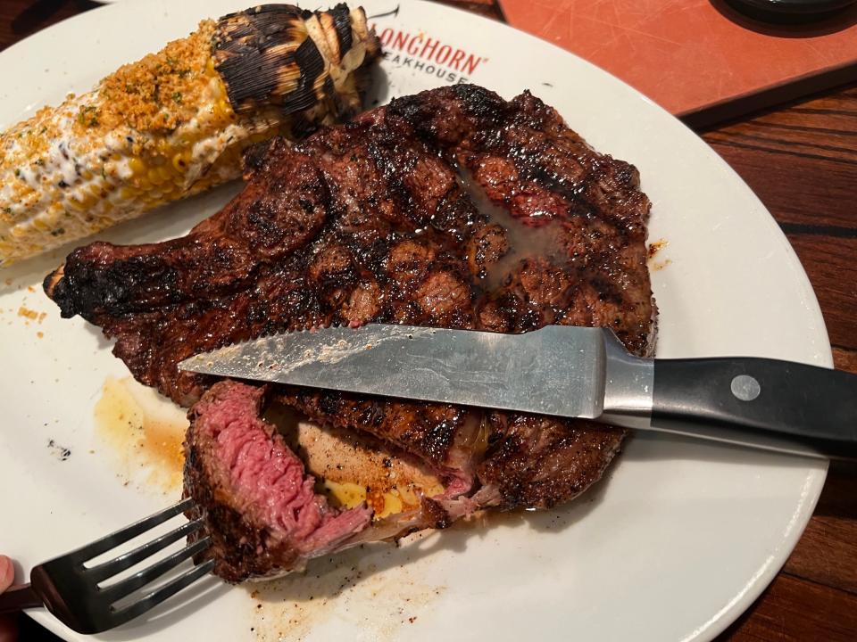 A Longhorn Steakhouse bone-in ribeye cooked medium-rare