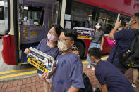 Passengers pose for photos near a double-decker bus they got on board, in Hong Kong, Saturday, Oct. 16, 2021. The 76-kilometer (47-mile), five-hour ride on a regular double-decker bus around the territory is meant to appeal to people who are easily lulled asleep by long rides. It was inspired by the tendency of tired commuters to fall asleep on public transit. The banners read: "The first in Hong Kong! Snooze bus tour." (AP Photo/Kin Cheung)