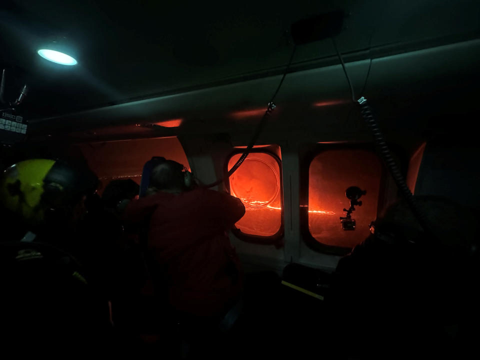 People watch from a helicopter as a volcano spews lava and smoke as it erupts, north of Grindavik, Reykjavik Peninsula, Iceland, obtained by Reuters December 19, 2023. Coast Guard/Iceland Sheet via REUTERS