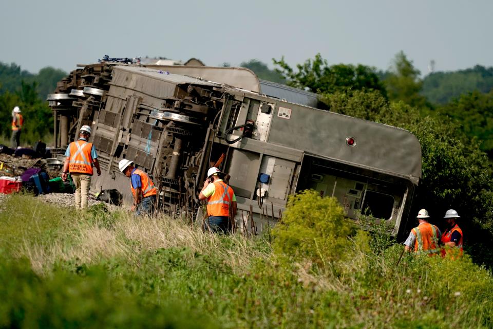 Workers inspect the scene of an Amtrak train that derailed after striking a dump truck near Mendon, Missouri.