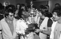 FILE - In this Aug. 29, 1977 file photo, New York Cosmos' soccer player Pele, center left, kisses his team's trophy, held up by team captain Werner Roth, at New York's Kennedy Airport as the team returns after winning the North American Soccer League Championship against the Seattle Sounders. On Oct. 23, 2020, the three-time World Cup winner Pelé turns 80 without a proper celebration amid the COVID-19 pandemic as he quarantines in his mansion in the beachfront city of Guarujá, where he has lived since the start of the pandemic. (AP Photo, File)