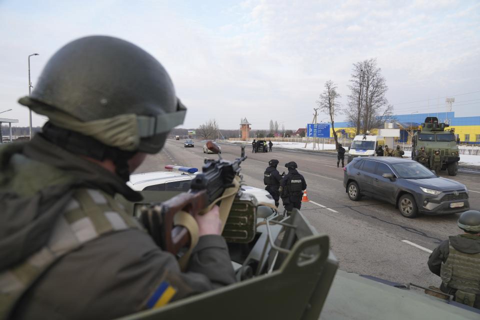 A Ukrainian National guard soldier, left, holds his weapon ready as he guards the mobile checkpoint with the Ukrainian Security Service agents and police officers in Kharkiv, Ukraine, Thursday, Feb. 17, 2022. Fears of a new war in Europe have resurged as U.S. President Joe Biden warned that Russia could invade Ukraine within days, and violence spiked in a long-running standoff in eastern Ukraine that some fear could be the spark for wider conflict. (AP Photo/Evgeniy Maloletka)