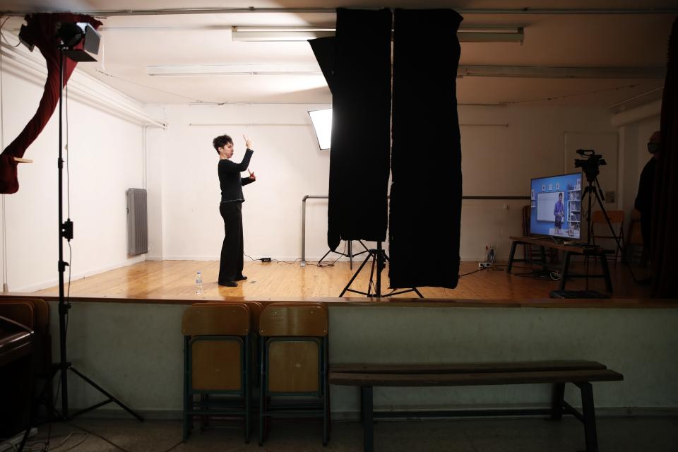 Sofia Roboli records sign language lessons that are broadcast on public television, at an elementary school in Athens, Friday, Nov. 20, 2020. Most other European countries have vowed to keep schools open, but the pandemic has hit Greece hard for the first time in recent weeks following a successful lockdown in the spring, overwhelming hospitals in parts of the country. State television is making and broadcasting lessons, while teachers sit in empty classrooms talking to remote students. Despite some problems, they say it keeps children in touch with their schools. (AP Photo/Thanassis Stavrakis)