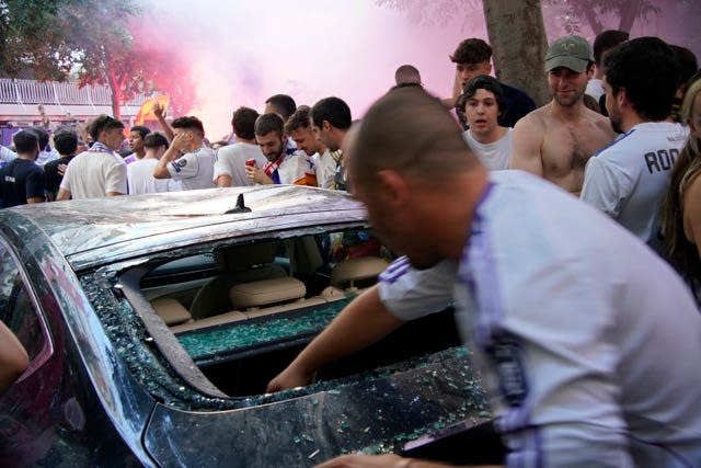 A man puts his hand inside a smashed car window outside the Bernabeu 