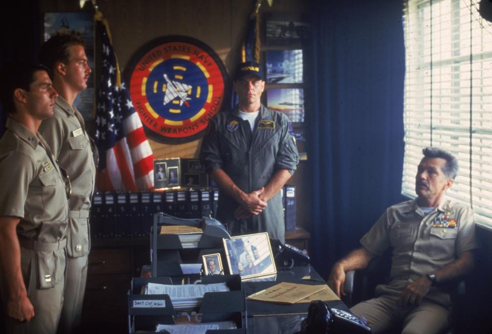 Jester (Michael Ironside, center) stands as Maverick (Tom Cruise, left) and Goose (Anthony Edwards) stand at attention at Viper's desk (Tom Skerritt) in "Top Gun."