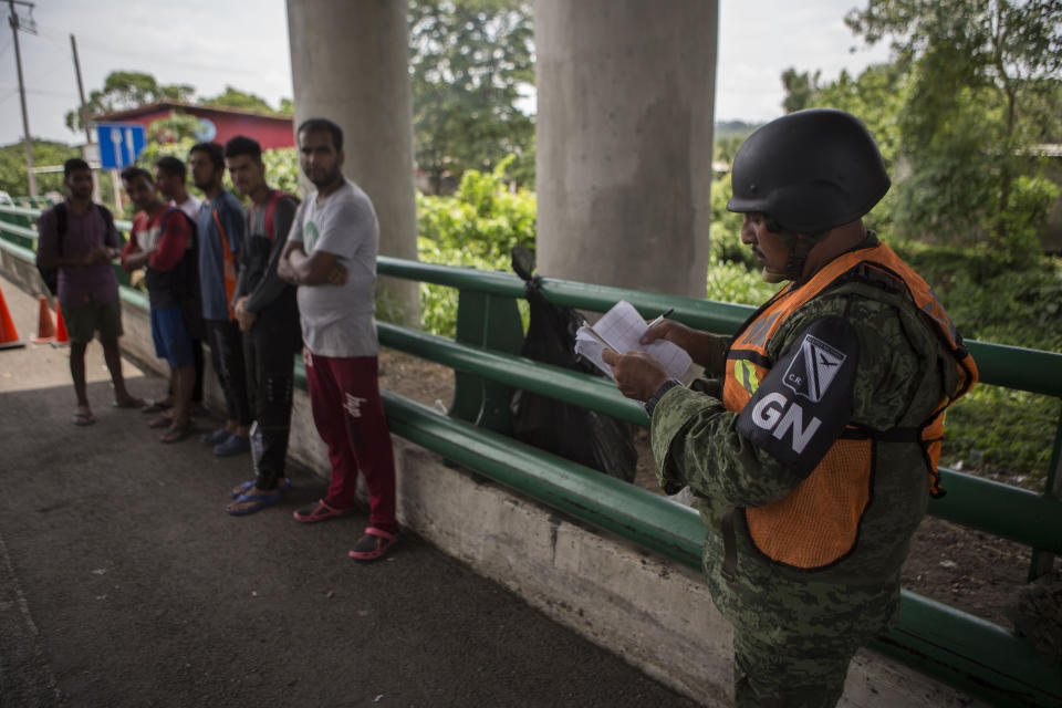 A Mexican National Guardsman stops a group of migrants from Bangladesh, India and Pakistan, at an immigration checkpoint known as Viva Mexico, near Tapachula, Mexico, Friday, June 21, 2019. Mexico's foreign minister says that the country has completed its deployment of some 6,000 National Guard members to help control the flow of Central American migrants headed toward the U.S. (AP Photo/Oliver de Ros)