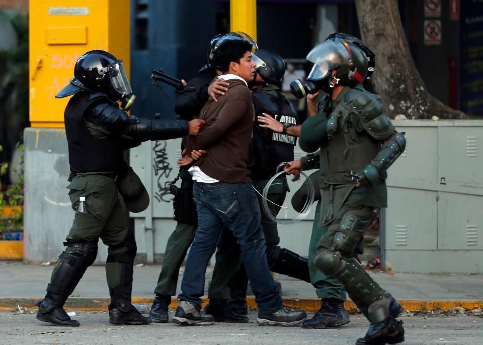 Un manifestante es detenido por efectivos de la Guardia Nacional durante protestas antigubernamentales en Caracas, Venezuela, el martes 4 de marzo de 2014. El miércoles se cumple un año del fallecimiento del presidente Hugo Chávez en tanto que su proyecto de la revolución bolivariano enfrenta sus mayores desafíos ante las inconformidades, incluida la escasez de alimentos básicos. (AP Foto/Fernando Llano)