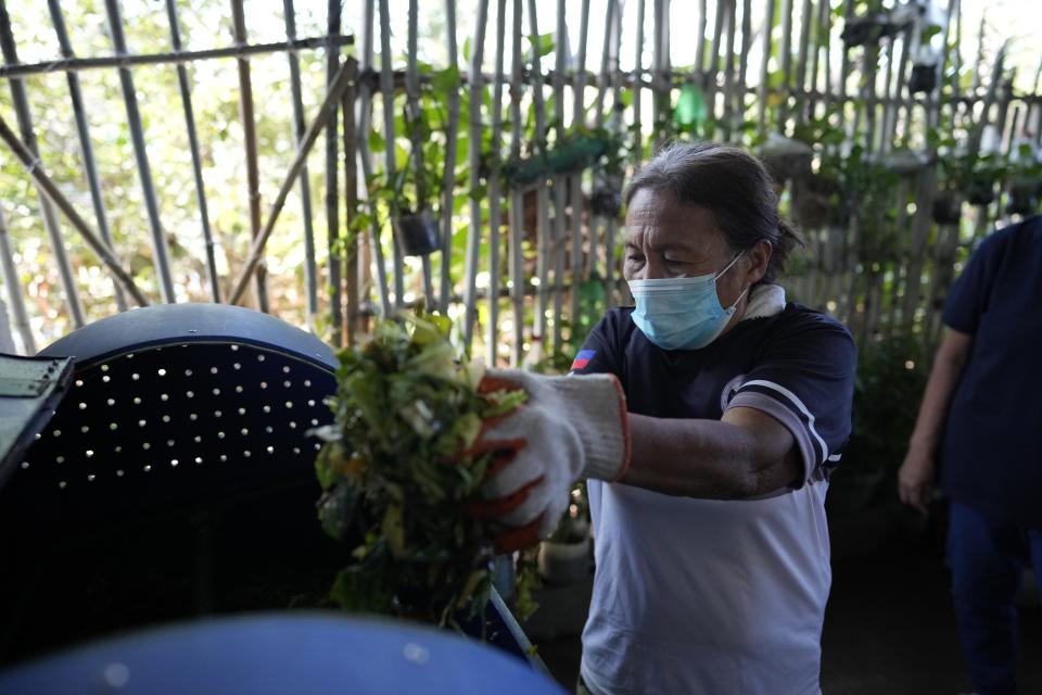 A worker places organic waste for processing at a recycling facility in Malabon, Philippines on Monday Feb. 13, 2023. Food waste emits methane as it breaks down and rots. Waste pickers are helping set up systems to segregate and collect organic waste, and establishing facilities to compost it. (AP Photo/Aaron Favila)