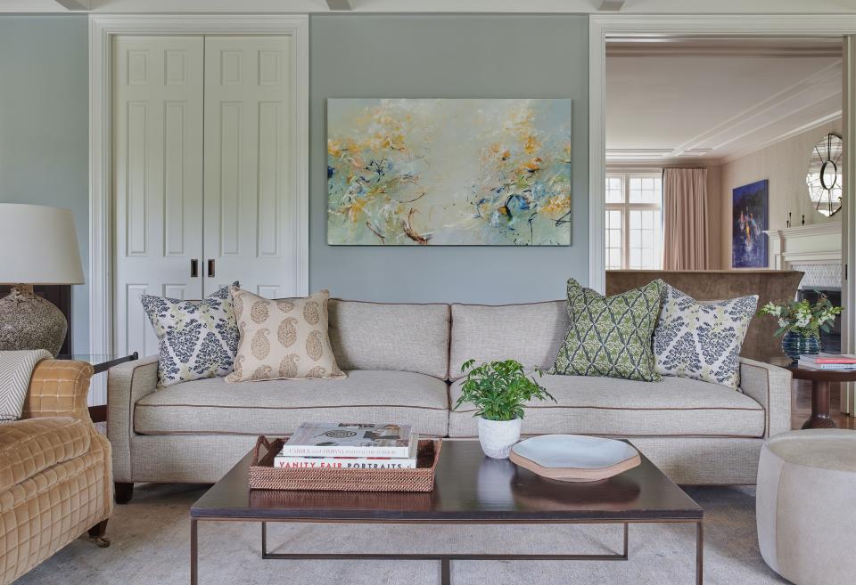 A custom sofa built by Hickory Chair in New York is the centerpiece of the family room. Upholstered in a Jane Churchill fabric with camel piping by Duralee Fabrics, the sofa faces a coffee table by Mitchell Gold + Bob Williams and is flanked by a George Smith chair from Ganley’s former London home. Michael Schultheis did the acrylic painting. The pillows are Hollywood at Home, while the wall color is Tranquility by Benjamin Moore.
