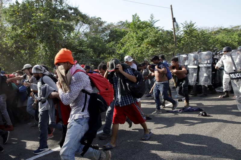 Migrants, mainly from Central America and marching in a caravan, react as members of the security forces approach them, near Frontera Hidalgo, Chiapa