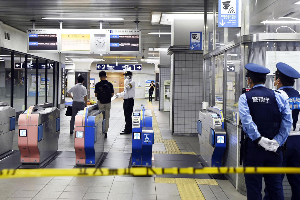 Policemen stand as ticket gates are sealed off at Soshigaya Okura Station after stabbing on a commuter train, in Tokyo Friday, Aug. 6, 2021. A man with a knife stabbed passengers on a commuter train Friday and was arrested by police after fleeing, fire department officials and news reports said. (Kyodo News via AP)