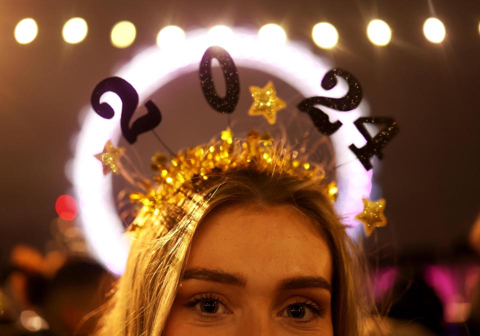 A reveller proudly shows off a 2024 headband ahead of the firework display (EPA)