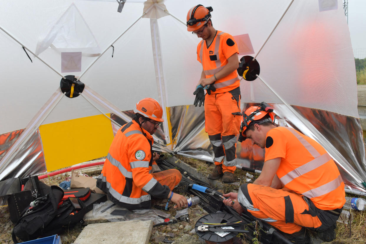 TOPSHOT - Workers operate to reconnect the signal box to the track in its technical ducts in Vald' Yerres, near Chartres on July 26, 2024, as France's high-speed rail network was hit by an attack disrupting the transport system, hours before the opening ceremony of the Paris 2024 Olympic Games. According to the French railway company SNCF, a massive attack on a large scale hit the high speed train network (TGV) on July 26, 2024, and many routes will have to be cancelled. The SNCF urged passengers to postpone their trips and stay away from train stations. (Photo by JEAN-FRANCOIS MONIER / AFP) (Photo by JEAN-FRANCOIS MONIER/AFP via Getty Images)