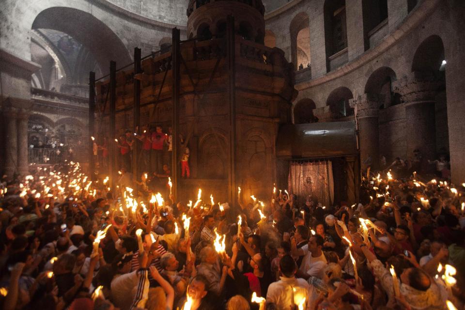 Peregrinos cristianos sostienen velas encendidas en el interior de la iglesia del Santo Sepulcro, en el sitio que según la tradición fue enterrado Jesús, durante la ceremonia del Fuego Sagrado en la Ciudad Vieja de Jerusalén, el sábado 19 de abril de 2014. (Foto AP/Dan Balilty)