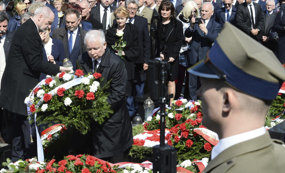 The ruling party Law and Justice leader and twin brother of the former Polish President Lech Kaczynski, Jaroslaw Kaczynski, second left, lays a wreath, as Defense Minister Antoni Macierewicz, left, holds a candle, during a ceremony at the Powazki cemetery to mark the seventh anniversary of the crash of the Polish government plane in Smolensk, Russia, that killed 96 people on board including Lech Kaczynski, in Warsaw, Poland, Monday, April 10, 2017. (AP Photo/Alik Keplicz)