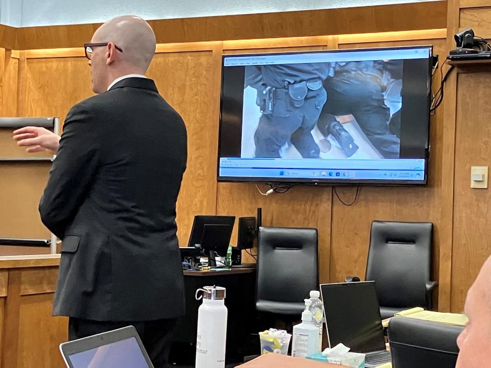 Drew Wood, of the Ohio Attorney General's office, asks a witness in the retrial of Mark Cooper in Richland County Common Pleas Court on Friday.  A video from the provincial jail can be seen in the background.