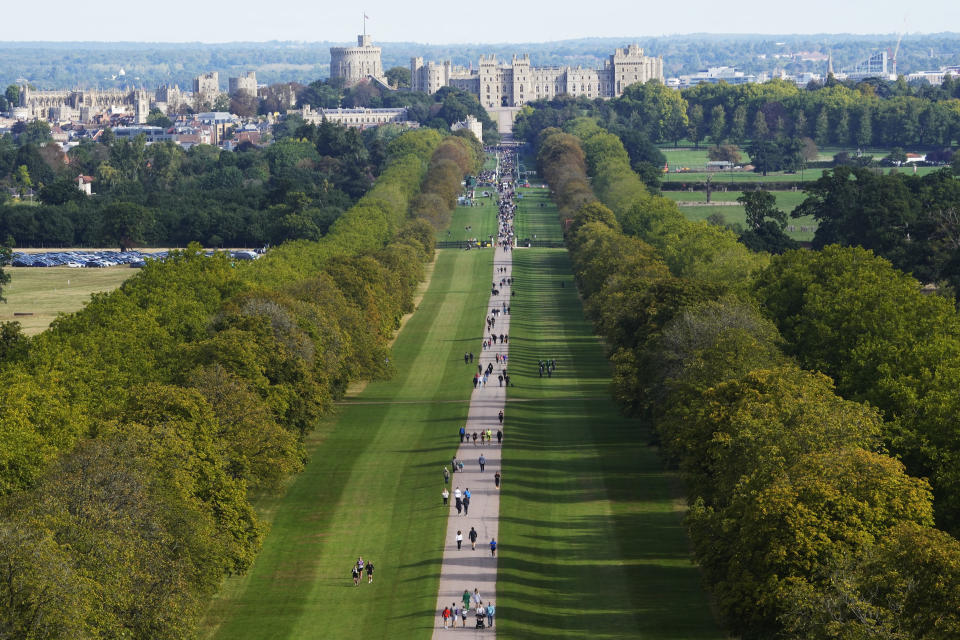 People make their way along the Long Walk towards Cambridge gate outside Windsor Castle to lay flowers for the late Queen Elizabeth II in Windsor, England, Sunday, Sept. 18, 2022. The Queen will lie in state in Westminster Hall for four full days before her funeral on Monday Sept. 19. (AP Photo/Gregorio Borgia)