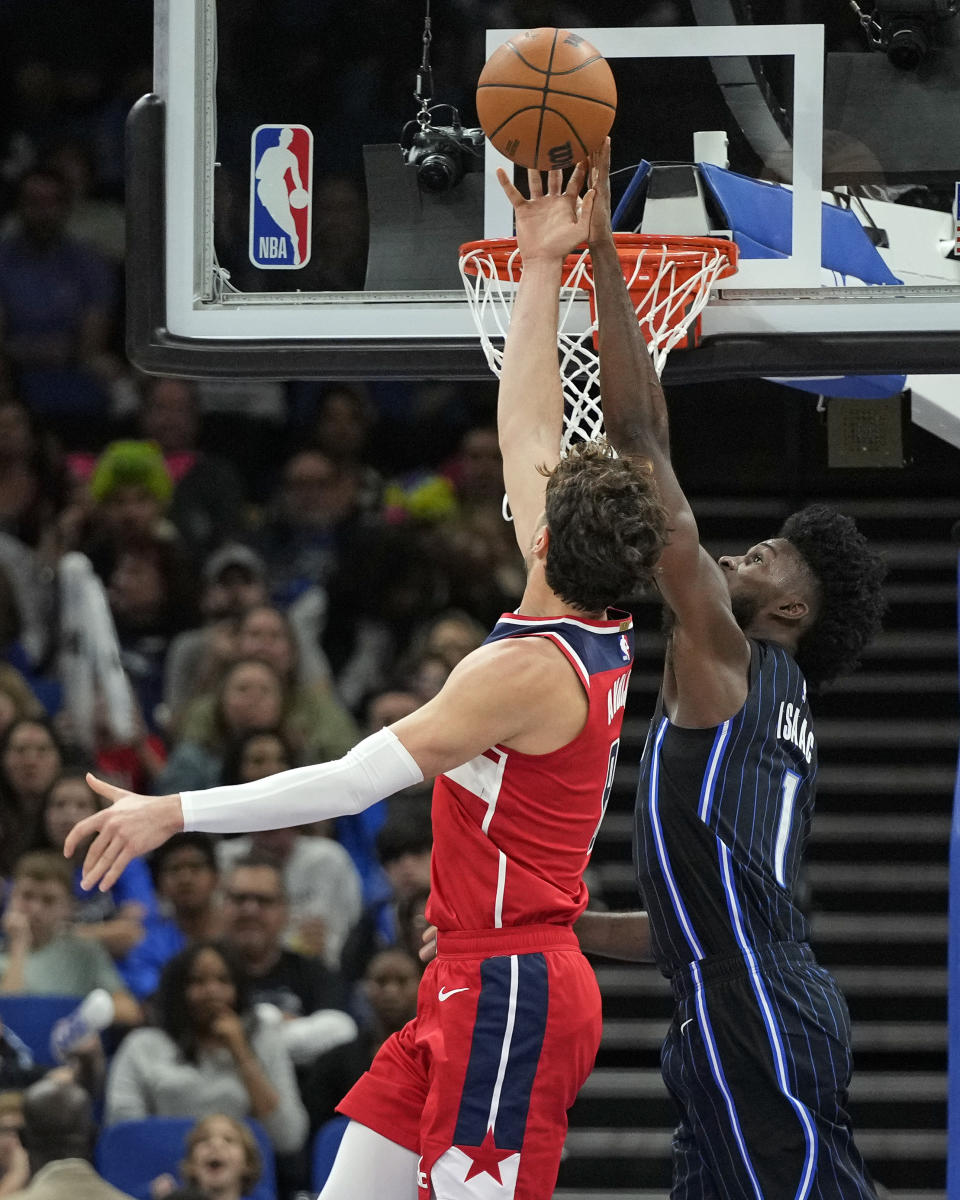 Orlando Magic forward Jonathan Isaac, right, blocks a shot by Washington Wizards forward Deni Avdija during the first half of an NBA basketball game Friday, Dec. 1, 2023, in Orlando, Fla. (AP Photo/John Raoux)