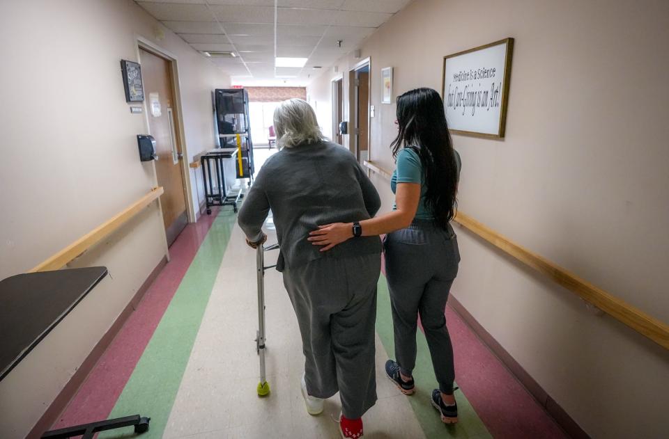 Jennifer Ferreira, program director at Linn Health and Rehabilitation, helps resident Hilda Silva to her room at Aldersbridge Communities in East Providence.