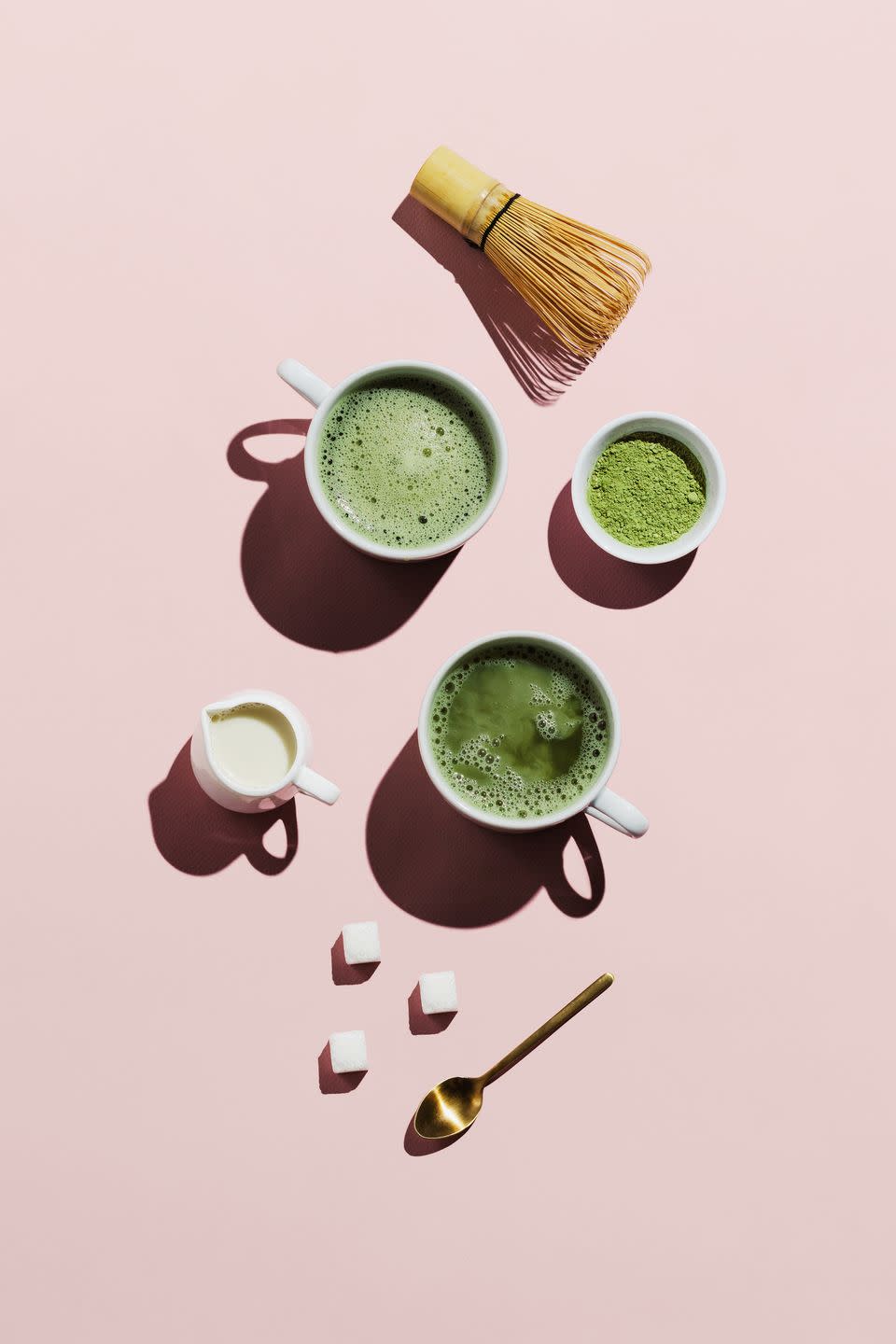 two matcha lattes with milk on pink background