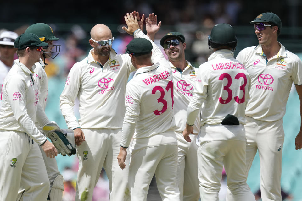 Australia's David Warner, center, celebrates with teammate Nathan Lyon after combining to take the wicket of Pakistan's Mohammad Rizwan on the fourth day of their cricket test match in Sydney, Saturday, Jan. 6, 2024. (AP Photo/Rick Rycroft)