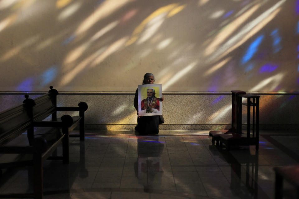 Adelina Hidalgo holds a photograph of Pope Benedict as she kneels inside the Metropolitan Cathedral in San Salvador