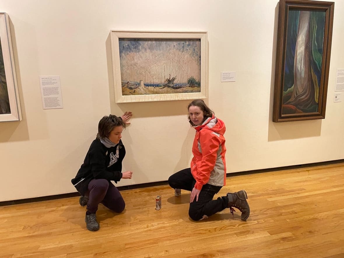 This photo provided to media from the group Stop Fracking Around shows Erin Fletcher, left, and Emily Kelsall, right, in front of the Emily Carr painting, Stumps and Sky, at the Vancouver Art Gallery on Saturday, Nov. 12, 2022. (Stop Fracking Around - image credit)