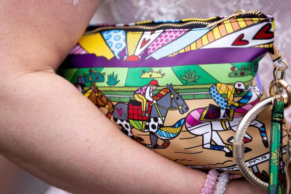 Whitney Cessell of Louisville holds a horse racing-themed bag on Derby Day at Churchill Downs.